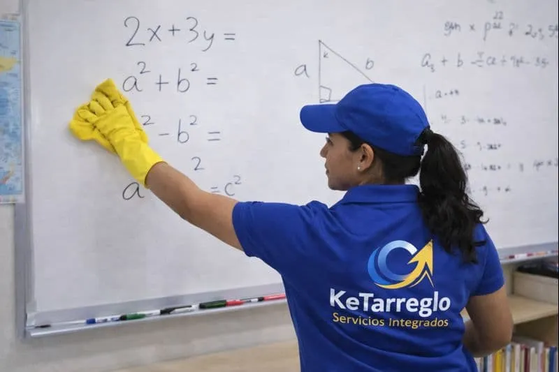 Mujer de servicio de limpieza aseando un salon de clases